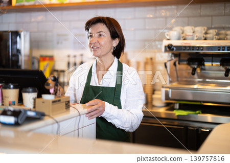 Senior woman salesperson works in cafeteria bakery shop Senior woman salesperson works in cafeteria bakery shop 139757816