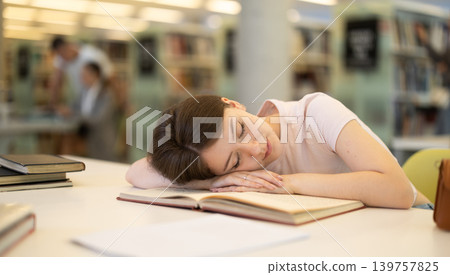 Female student tired and lay down on table in library 139757825