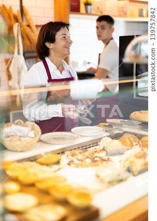 Elderly woman puts pastries on plate in cafe 139757842