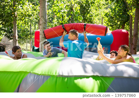 Playful man fighting off friends with inflatable log while guarding toy chickens Playful man fighting off friends with inflatable log while guarding toy chickens 139757860