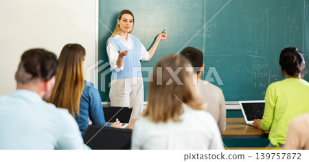 Woman teacher explaining lesson to students Woman teacher explaining lesson to students 139757872