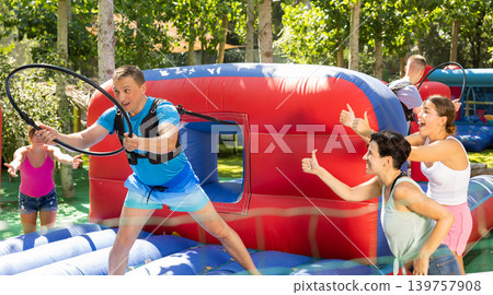 Man playing tug of war game with hoop on playground in amusement park Man playing tug of war game with hoop on playground in amusement park 139757908