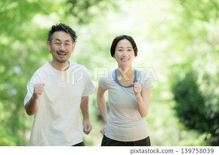 一對夫婦喜歡在綠樹環繞的公園裡慢跑、跑步和散步,享受健康積極的生活方式。 一對夫婦喜歡在綠樹環繞的公園裡慢跑、跑步和散步,享受健康積極的生活方式。 139758039
