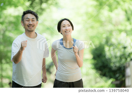 一對夫婦喜歡在綠樹環繞的公園裡慢跑、跑步和散步,享受健康積極的生活方式。 一對夫婦喜歡在綠樹環繞的公園裡慢跑、跑步和散步,享受健康積極的生活方式。 139758040