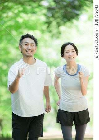 A healthy, active lifestyle for a couple enjoying jogging, running, and walking in a park surrounded by fresh greenery. A healthy, active lifestyle for a couple enjoying jogging, running, and walking in a park surrounded by fresh greenery. 139758043