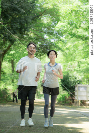一對熱愛跑步的健康夫婦在綠樹環繞的公園裡享受慢跑、跑步和散步:這是一種全身運動的生活方式。 一對熱愛跑步的健康夫婦在綠樹環繞的公園裡享受慢跑、跑步和散步:這是一種全身運動的生活方式。 139758045