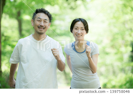 一對夫婦在綠樹環繞的公園裡慢跑、跑步和散步，展現了健康積極的生活方式。 （攝影機拍攝） 139758046