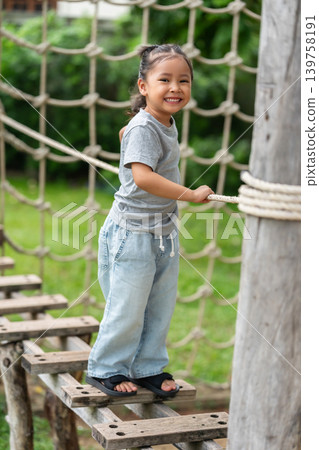 preschool child girl walking on a wooden balancing bridge at outdoor playground preschool child girl walking on a wooden balancing bridge at outdoor playground 139758191