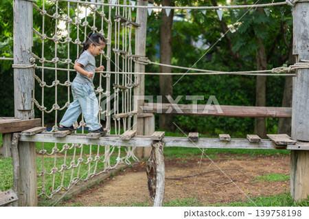 preschool child girl walking on a wooden balancing bridge at outdoor playground preschool child girl walking on a wooden balancing bridge at outdoor playground 139758198