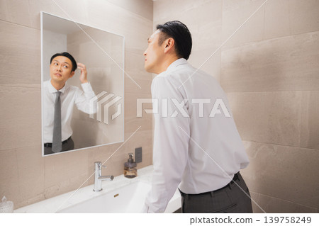 A businessman getting ready in the bathroom. A businessman getting ready in the bathroom. 139758249