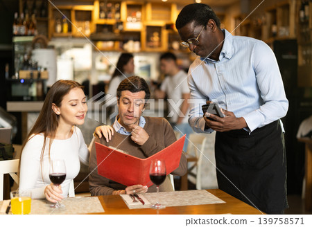 African man listen to restaurant couple customer, writes down order African man listen to restaurant couple customer, writes down order 139758571