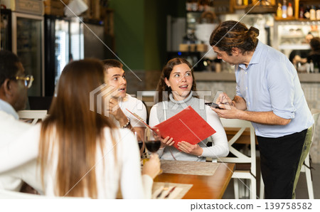 Waiter takes an order from a woman and a group of friends 139758582