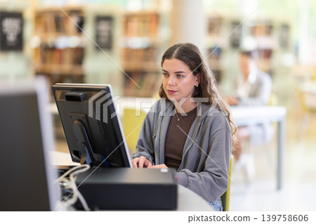 Female student works at computer in library Female student works at computer in library 139758606
