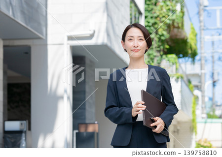 拿著文件的微笑的女商人 拿著文件的微笑的女商人 139758810