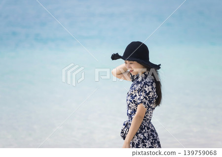 A young woman wearing a straw hat walking along the beach A young woman wearing a straw hat walking along the beach 139759068