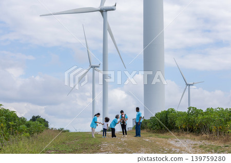 Family with daughter walking on field on wind farm.  139759280