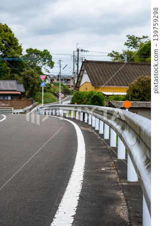 一條蜿蜒的鄉村公路,兩側設有連續的護欄。 一條蜿蜒的鄉村公路,兩側設有連續的護欄。 139759298