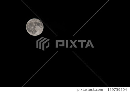一輪滿月懸掛在漆黑的夜空中,旁邊留有大片空白區域。 一輪滿月懸掛在漆黑的夜空中,旁邊留有大片空白區域。 139759304