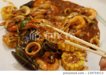 Chopsticks Picking Shrimp from Seafood Stir-Fry Dish Chopsticks Picking Shrimp from Seafood Stir-Fry Dish 139759513