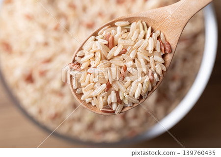 Close up of organic Thai brown rice in a wooden spoon, Asian food ingredient, Top view Close up of organic Thai brown rice in a wooden spoon, Asian food ingredient, Top view 139760435
