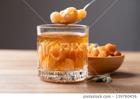 Longan juice in glass with dried longan fruit on wooden background Longan juice in glass with dried longan fruit on wooden background 139760456
