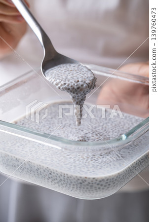 Chia seeds soaking in milk in a glass bowl with spoon holding by hand 139760473