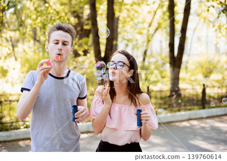 Two friends having fun together blowing soap bubbles in the park 139760614