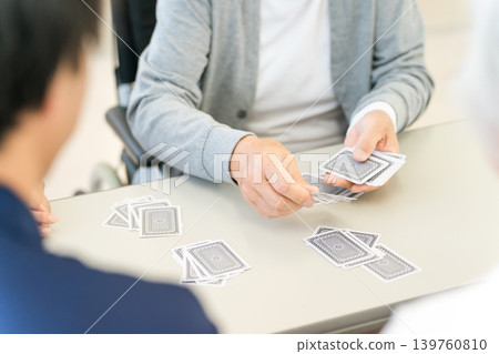 Elderly people and caregivers playing cards at a group home/nursing home. Elderly people and caregivers playing cards at a group home/nursing home. 139760810