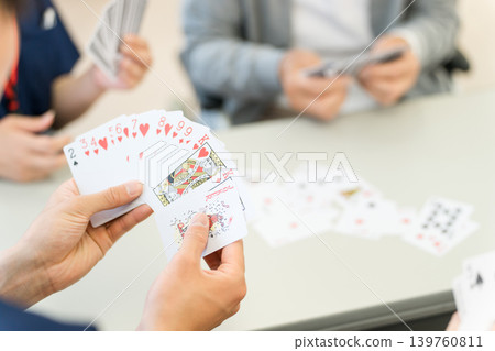 Elderly people playing cards in a group home or nursing home and a female caregiver 139760811