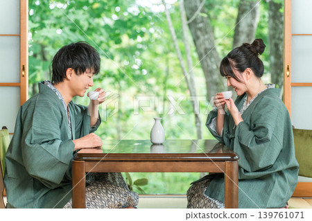Men and women in yukatas pouring sake in a Japanese-style room at a ryokan, married couple, couple (sake) 139761071