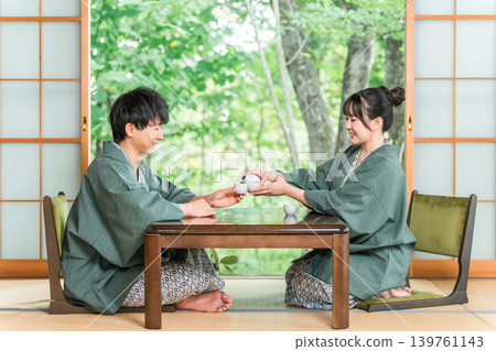 穿著浴衣的男女在日式旅館的房間裡端著飲料,已婚夫婦,情侶 穿著浴衣的男女在日式旅館的房間裡端著飲料,已婚夫婦,情侶 139761143