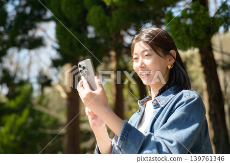 Japanese woman looking at her smartphone in a park Japanese woman looking at her smartphone in a park 139761346