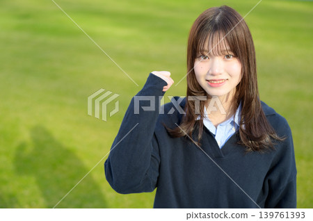 日本女高中生在草地上擺出勝利姿勢。 139761393