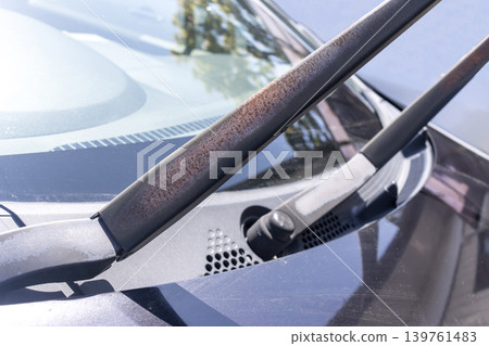 A car wiper arm with peeling paint and exposed brown rust due to age-related deterioration. A car wiper arm with peeling paint and exposed brown rust due to age-related deterioration. 139761483