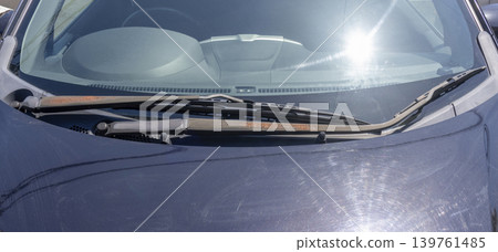 A car wiper arm with peeling paint and exposed brown rust due to age-related deterioration. 139761485