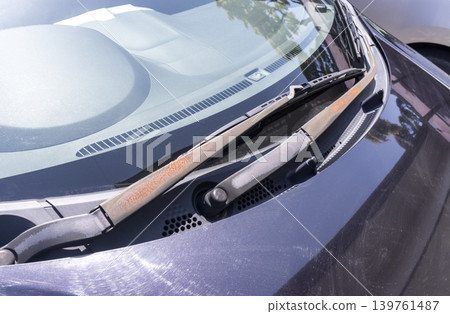 A car wiper arm with peeling paint and exposed brown rust due to age-related deterioration. A car wiper arm with peeling paint and exposed brown rust due to age-related deterioration. 139761487
