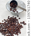 A measuring spoon and scattered roasted coffee beans on a wooden stand. 139761740