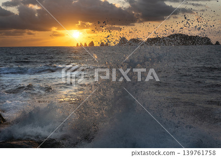 A view of the sunrise over the Nanatsu-iwa rocks off the coast of Hyuga-nada Sea and the crashing waves from Inozakibana Park Campground in Nichinan City, Miyazaki Prefecture. A view of the sunrise over the Nanatsu-iwa rocks off the coast of Hyuga-nada Sea and the crashing waves from Inozakibana Park Campground in Nichinan City, Miyazaki Prefecture. 139761758