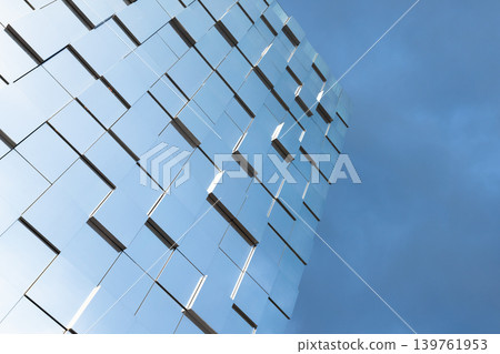 Modern glass facade of a high-rise building reflects a clear blue sky Modern glass facade of a high-rise building reflects a clear blue sky 139761953