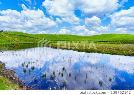 Early summer on the Soni Plateau; white clouds floating in the blue sky reflected on the surface of the Okame Pond, which I have returned to. Northwest direction. Early summer on the Soni Plateau; white clouds floating in the blue sky reflected on the surface of the Okame Pond, which I have returned to. Northwest direction. 139762142