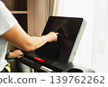 Woman setting on a treadmill's touchscreen before starting a cardio workout. 139762262