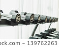 A row of black dumbbells on a storage rack in a fitness center. 139762263