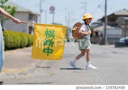 Elementary school students on their way to and from school and a flag for traffic safety monitoring. Elementary school students on their way to and from school and a flag for traffic safety monitoring. 139762480