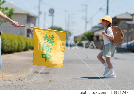 Elementary school students on their way to and from school and a flag for traffic safety monitoring. Elementary school students on their way to and from school and a flag for traffic safety monitoring. 139762481