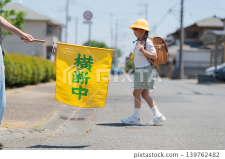 Elementary school students on their way to and from school and a flag for traffic safety monitoring. Elementary school students on their way to and from school and a flag for traffic safety monitoring. 139762482