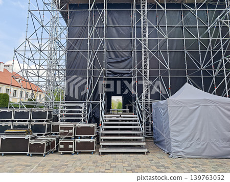 Metal stairs leading to an outdoor event stage during setup. Metal stairs leading to an outdoor event stage during setup. 139763052