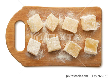 Cubes of Turkish delight sprinkled with powdered sugar on a wooden board isolated on a white. Top view Cubes of Turkish delight sprinkled with powdered sugar on a wooden board isolated on a white. Top view 139763132