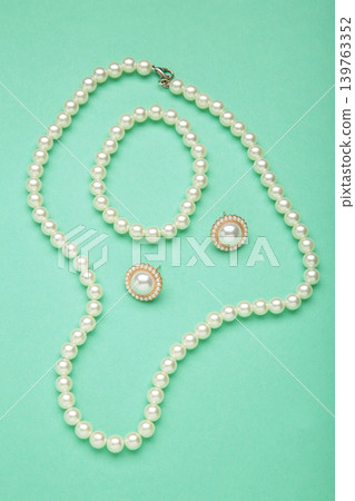 Beautiful pearl earring and necklace on mint background. Vertical photo Beautiful pearl earring and necklace on mint background. Vertical photo 139763352