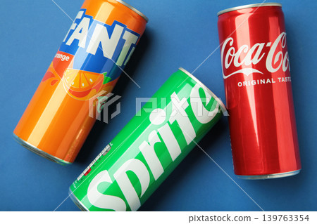 Mykolaiv, Ukraine - March 25, 2026: Iron cans of Coca Cola, Fanta and Sprite drink on blue background. Mykolaiv, Ukraine - March 25, 2026: Iron cans of Coca Cola, Fanta and Sprite drink on blue background. 139763354