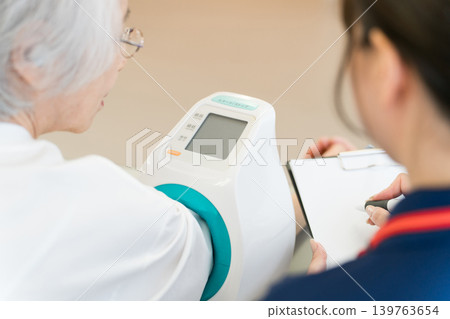 老年婦女用血壓計測量血壓,護士做筆記,女性護理人員 老年婦女用血壓計測量血壓,護士做筆記,女性護理人員 139763654